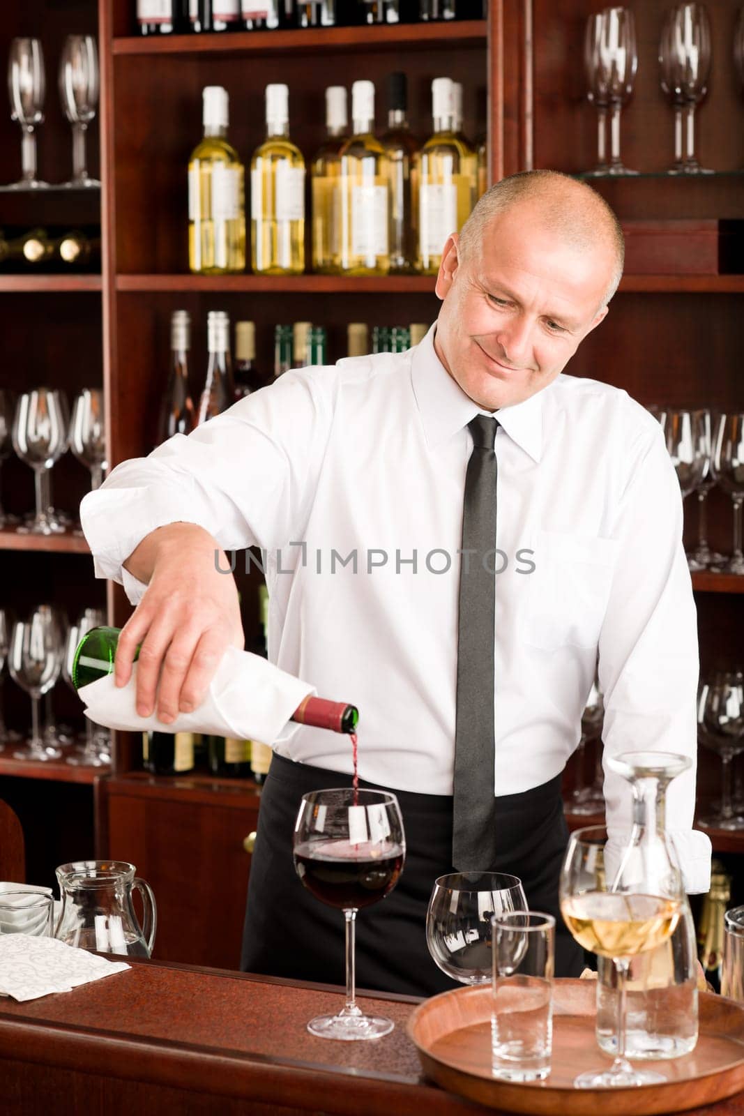At the bar - waiter pour red wine in glass restaurant