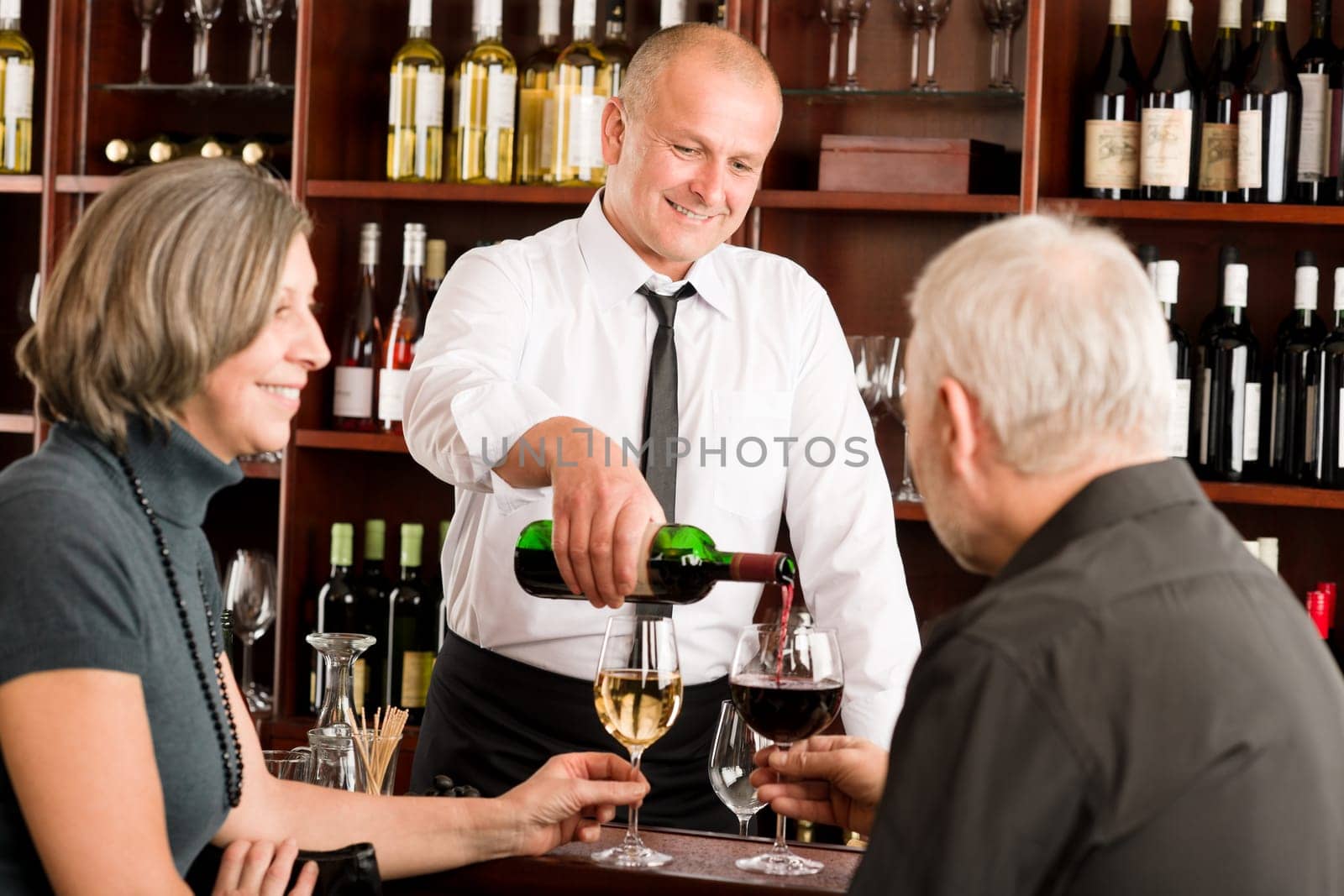 Wine bar senior couple enjoy drink professional barman pour glass