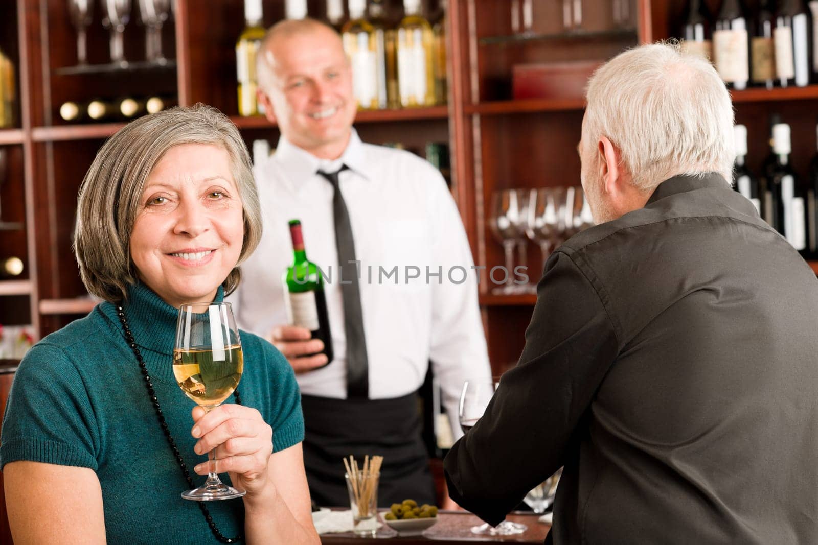Wine bar senior couple enjoy drink smiling barman discussing