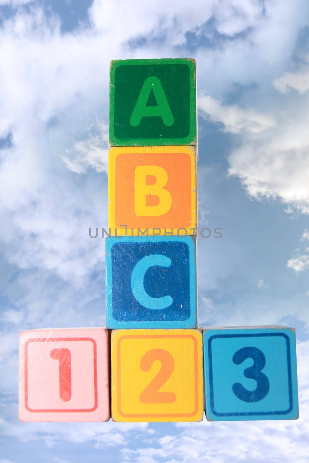 toy letter and number blocks against a cloudy background that spell abc 123 with clipping path