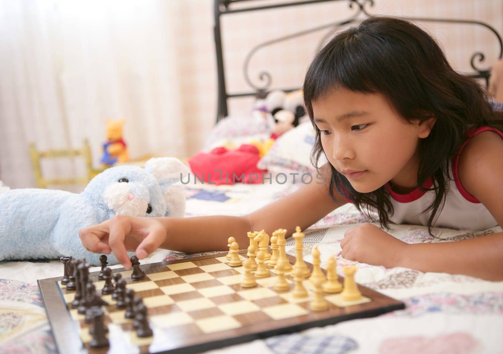 asian little girl playing home chess with teddy blue rabbit in her bedroom
