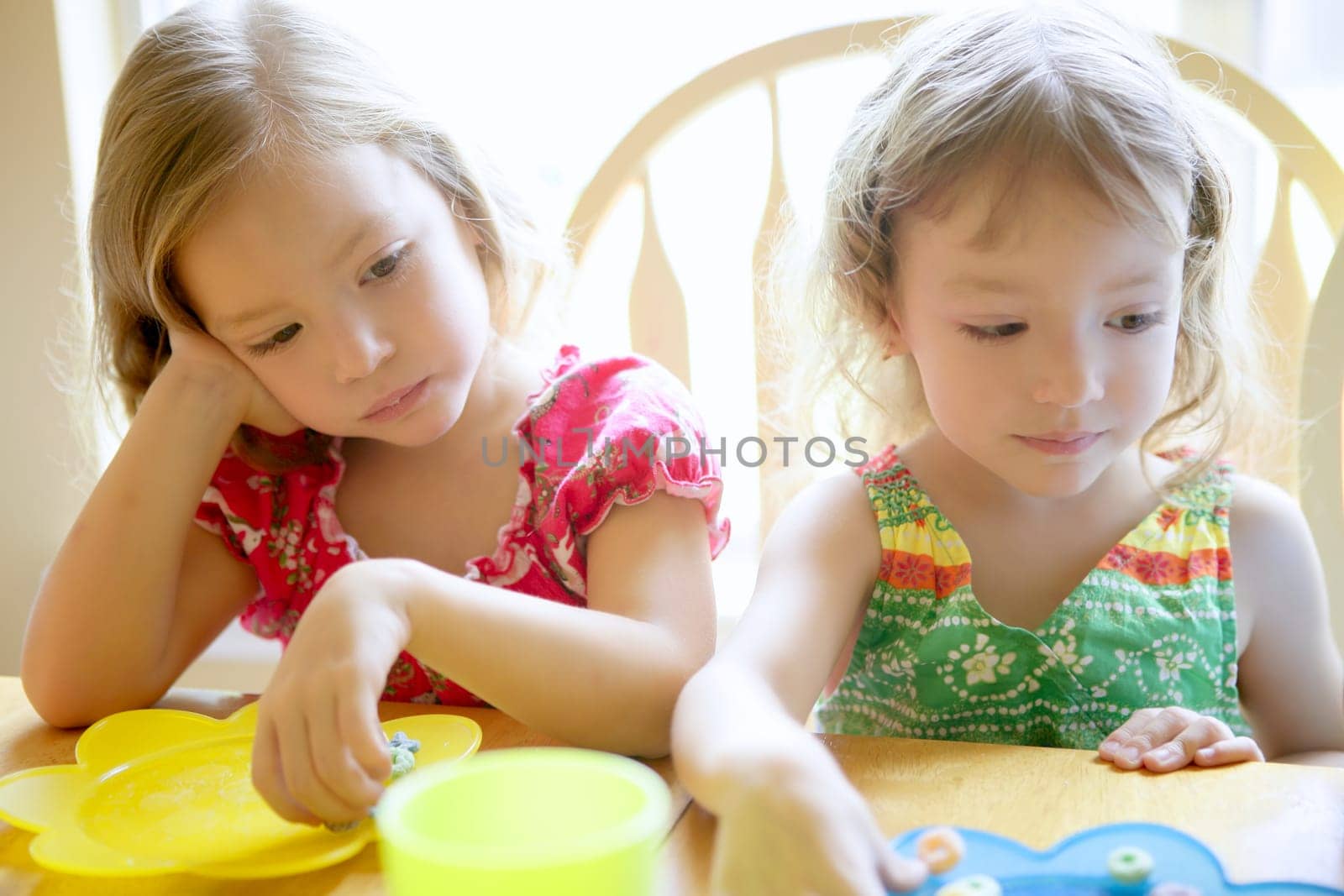 Two little sister girls eating together on the table