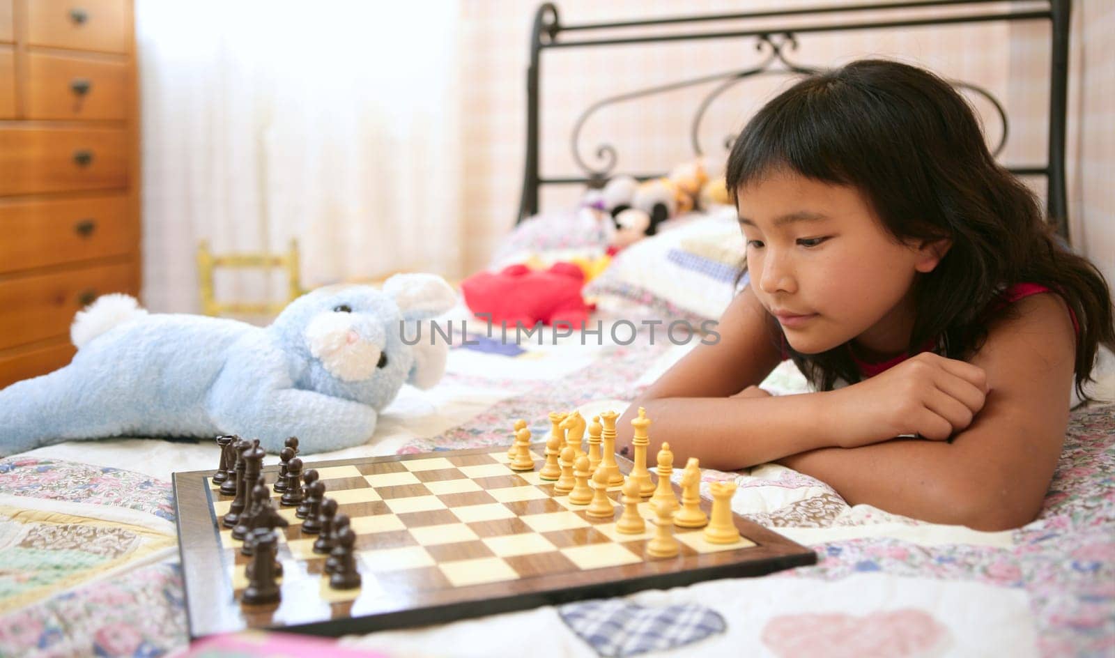asian little girl playing home chess with teddy blue rabbit in her bedroom