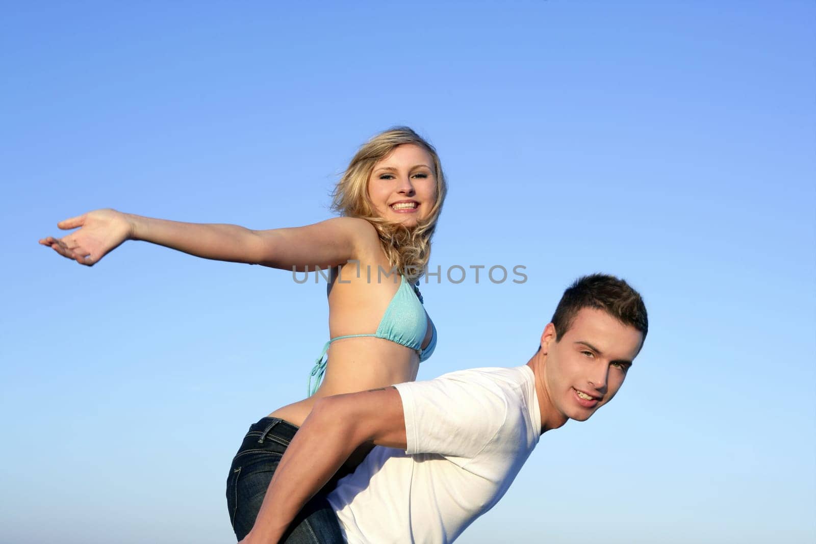 Young beautiful couple playing on the blue beach