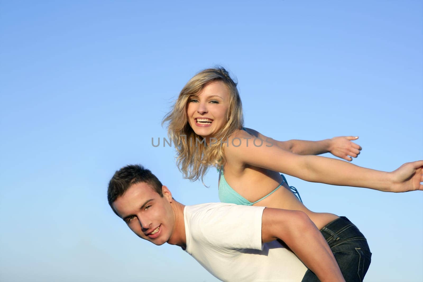Happy beautiful young couple playing together over blue sky