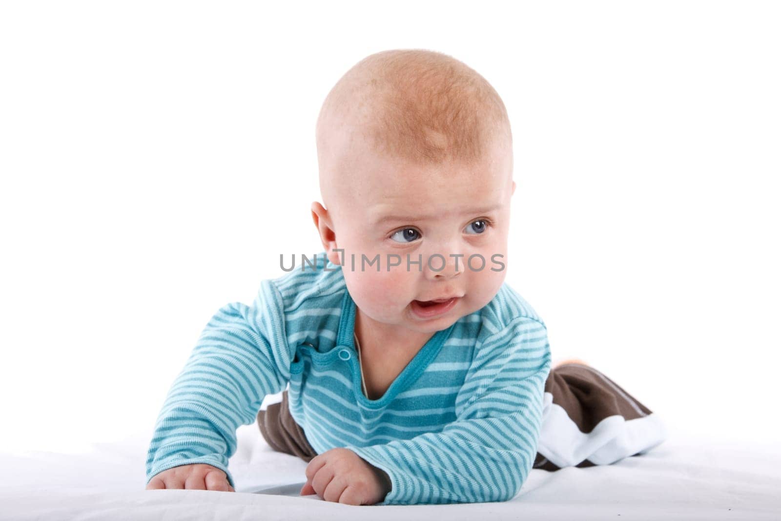 The nice small child in striped rompers lays on a stomach on a white background.