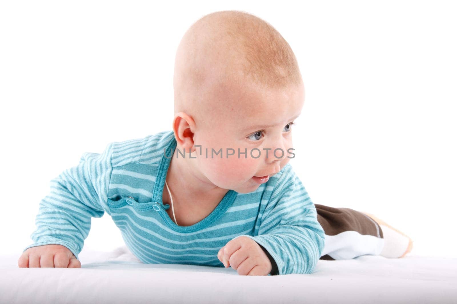The nice small child in striped rompers lays on a stomach on a white background.