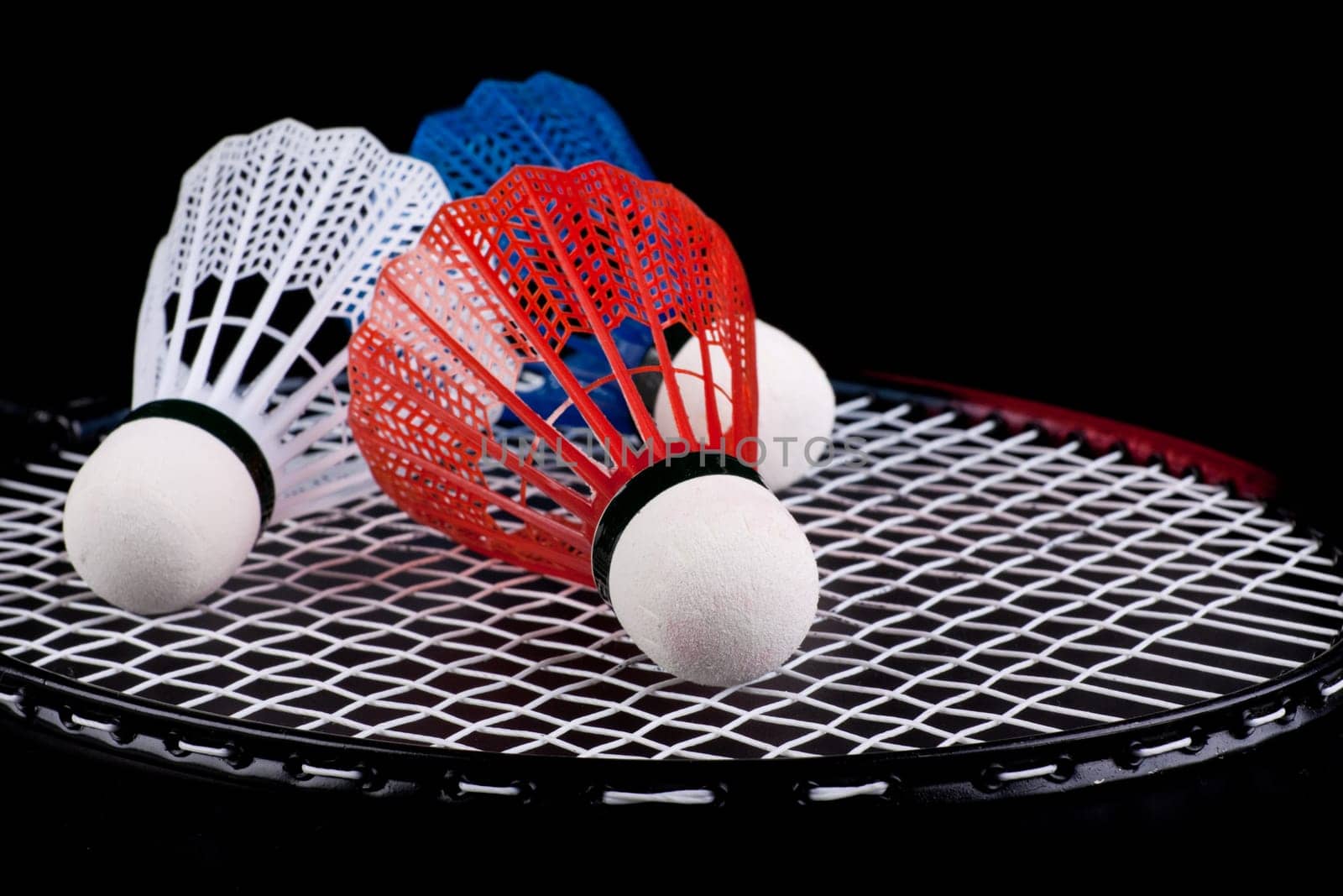 Shuttlecock and badminton racket over black background