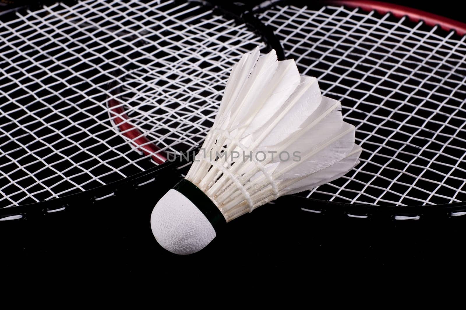 Shuttlecock and badminton racket over black background