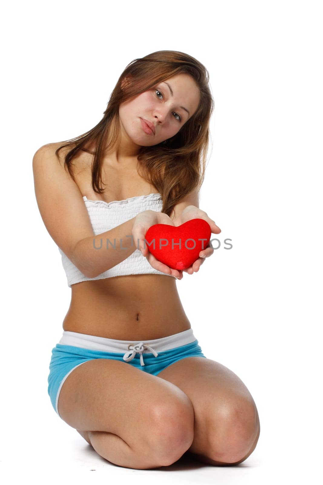 The beautiful girl holds in hands a red heart on a white background.