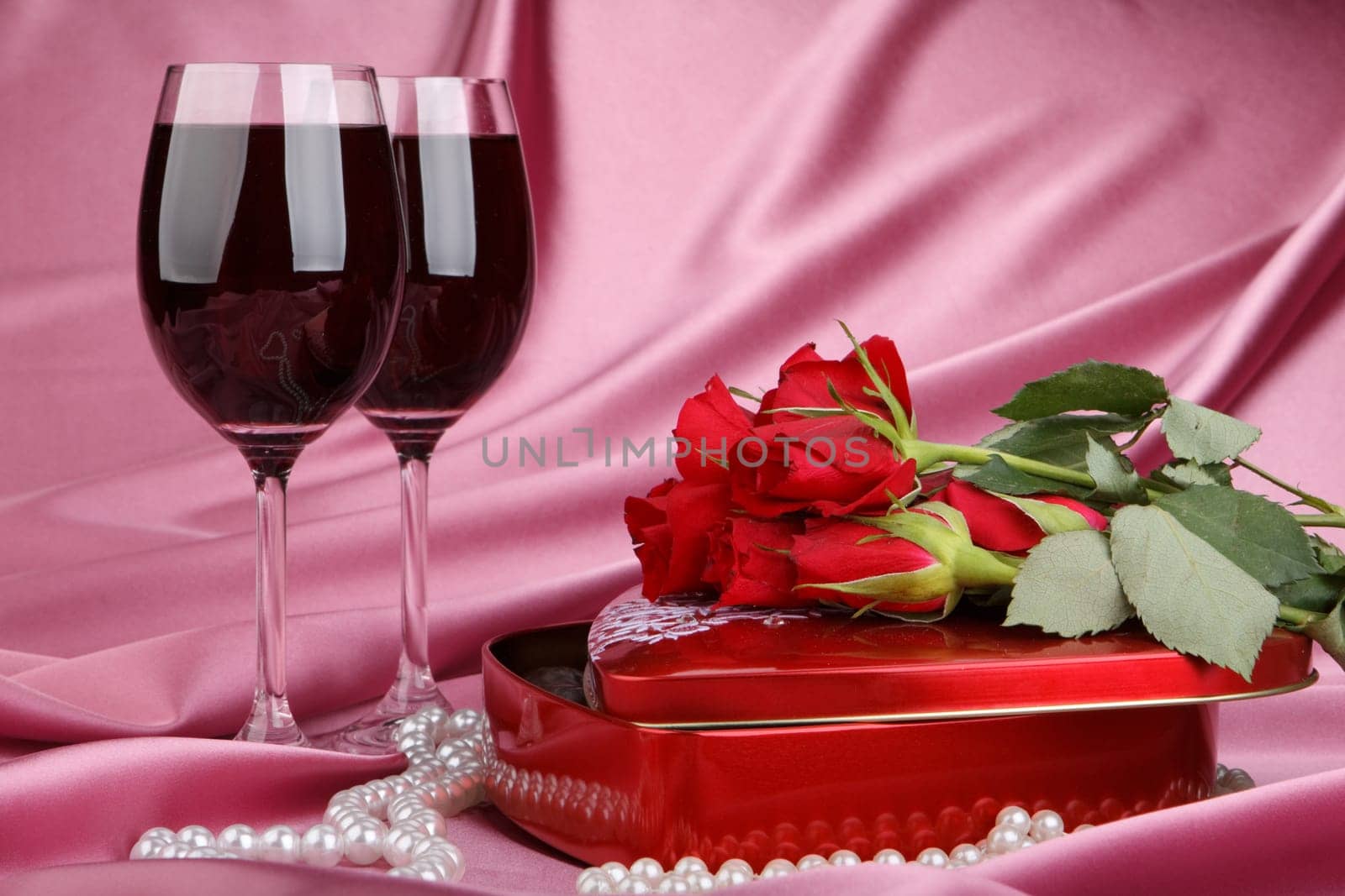 Heart-shaped red box with sweets, two glasses of red wine  and bunch of flowers. Valentine&#039 s day card.