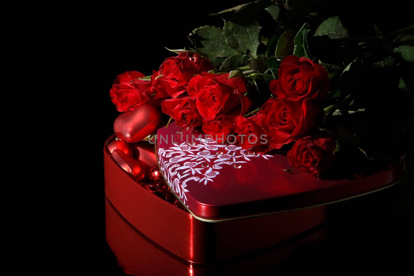 Heart-shaped red box and flowers on a black background. Valentine&#039 s day card.