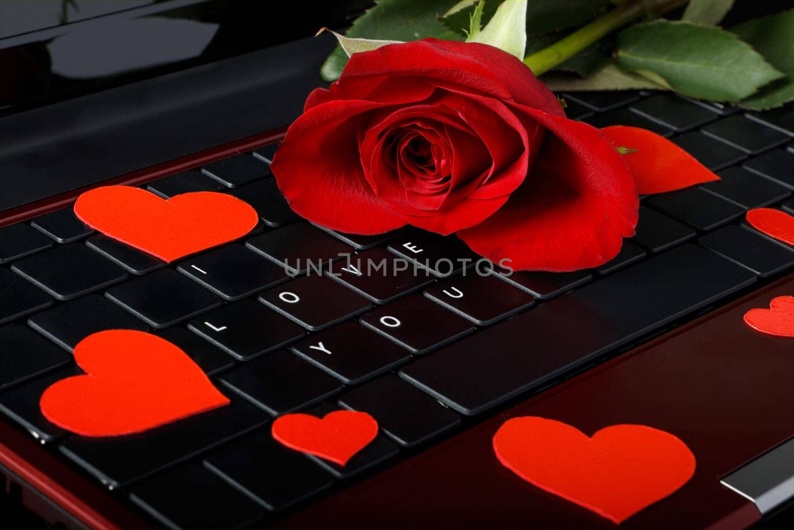 Modern notebook with sign "I Love You"" on keyboard and rose on a black background"