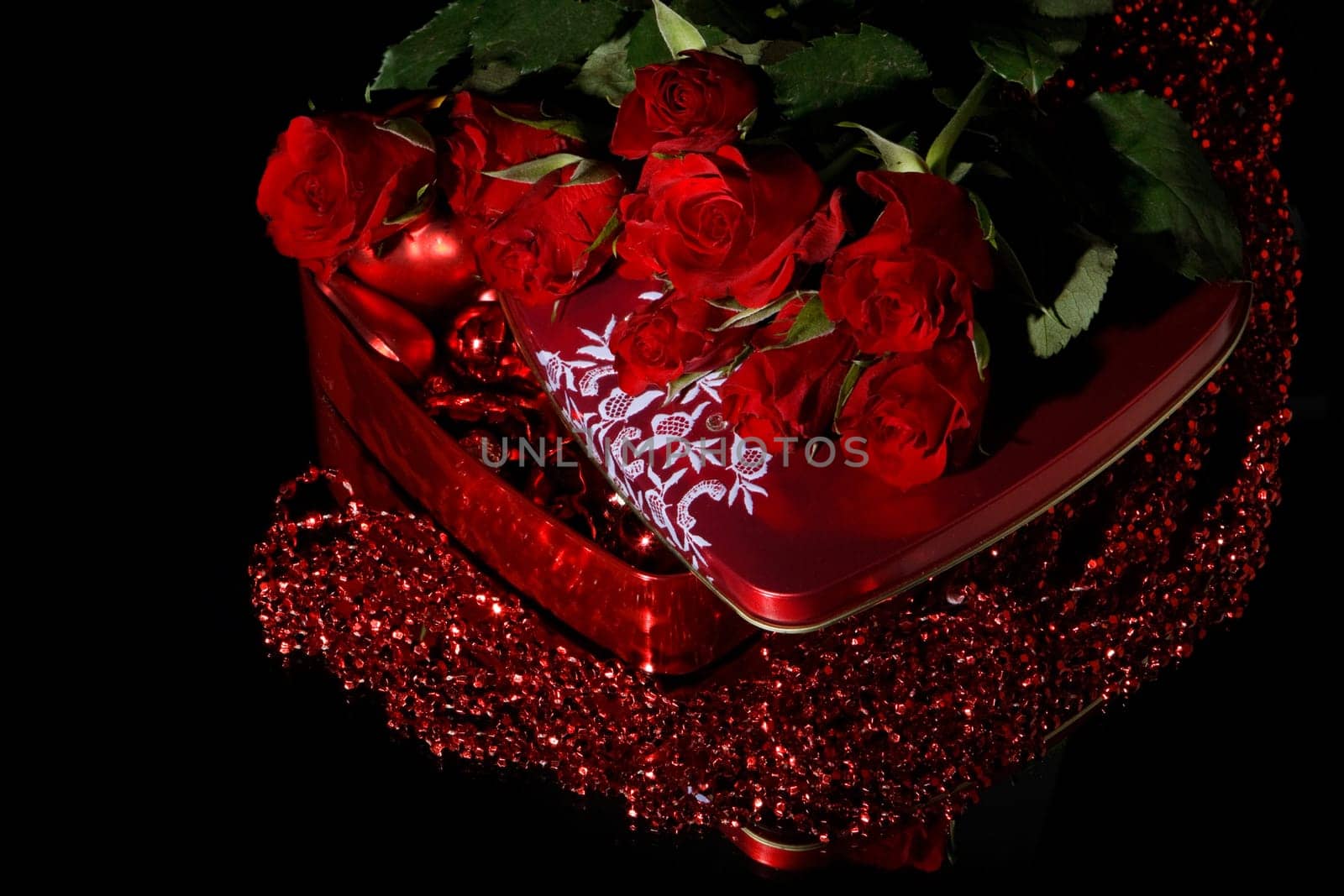 Heart-shaped red box and flowers on a black background. Valentine&#039 s day card.