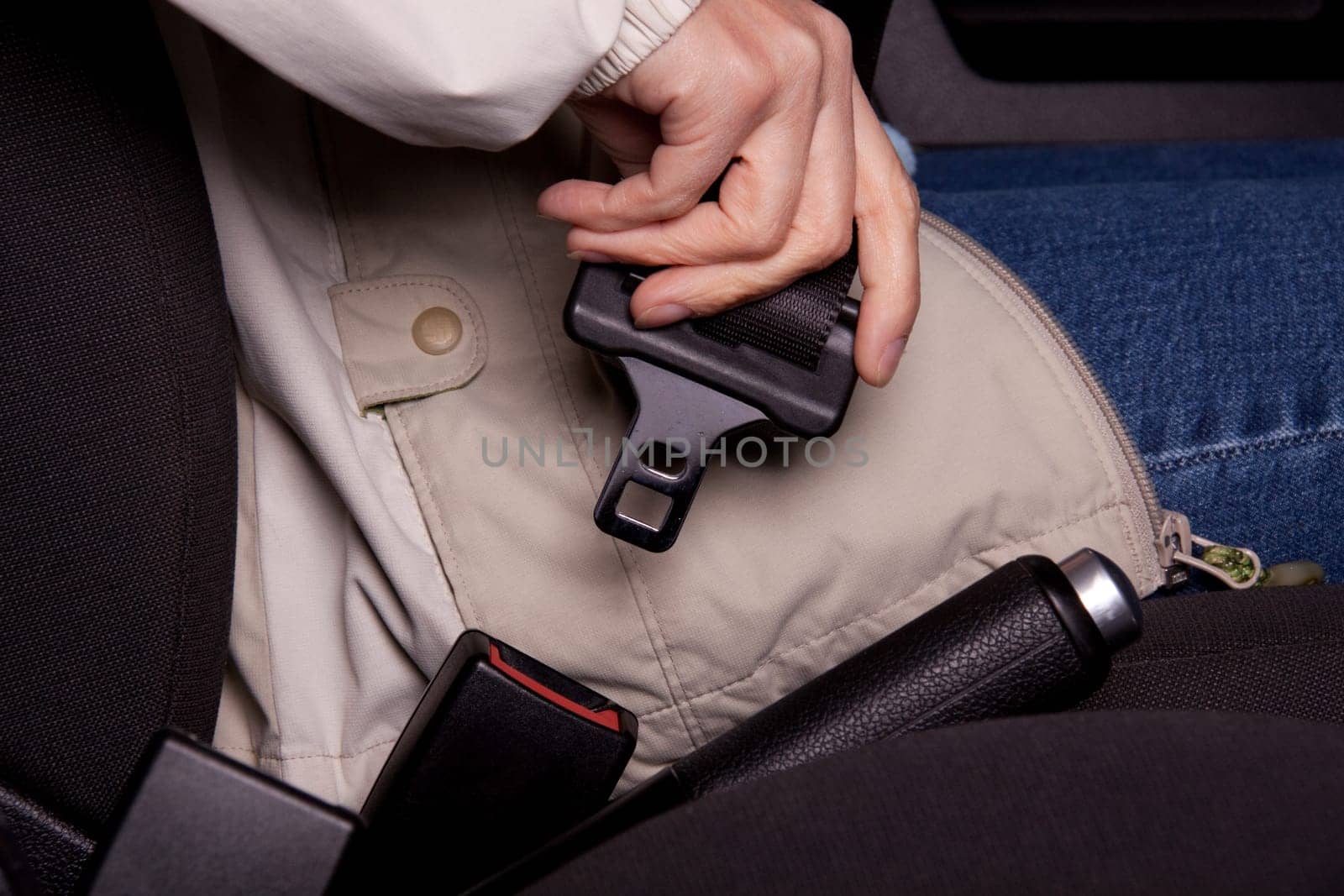 Female hand fastening a seat belt in the car.