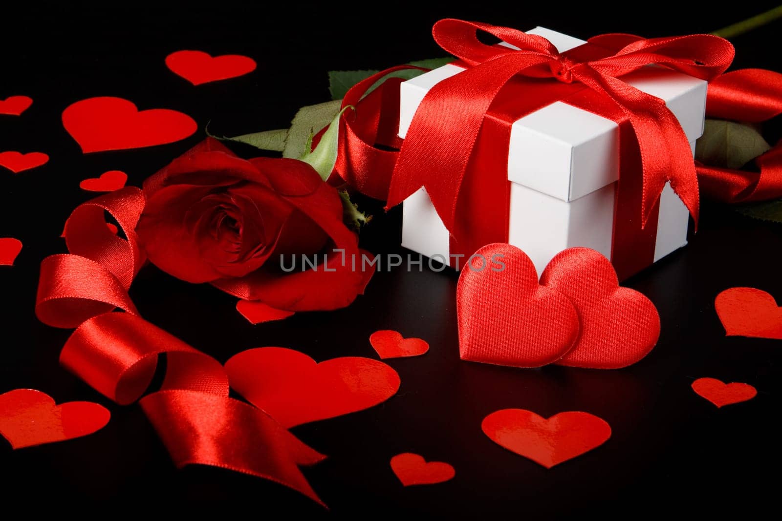 Gift box, red hearts and rose on a black background. Valentine&#039 s day card.