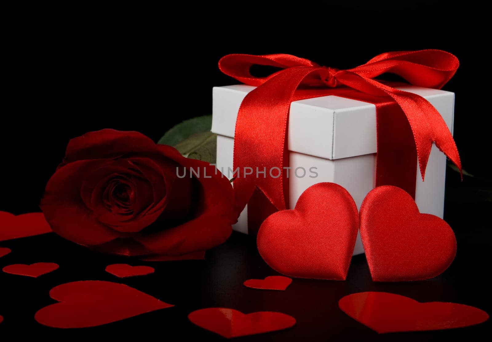 Gift box, red hearts and rose on a black background. Valentine&#039 s day card.
