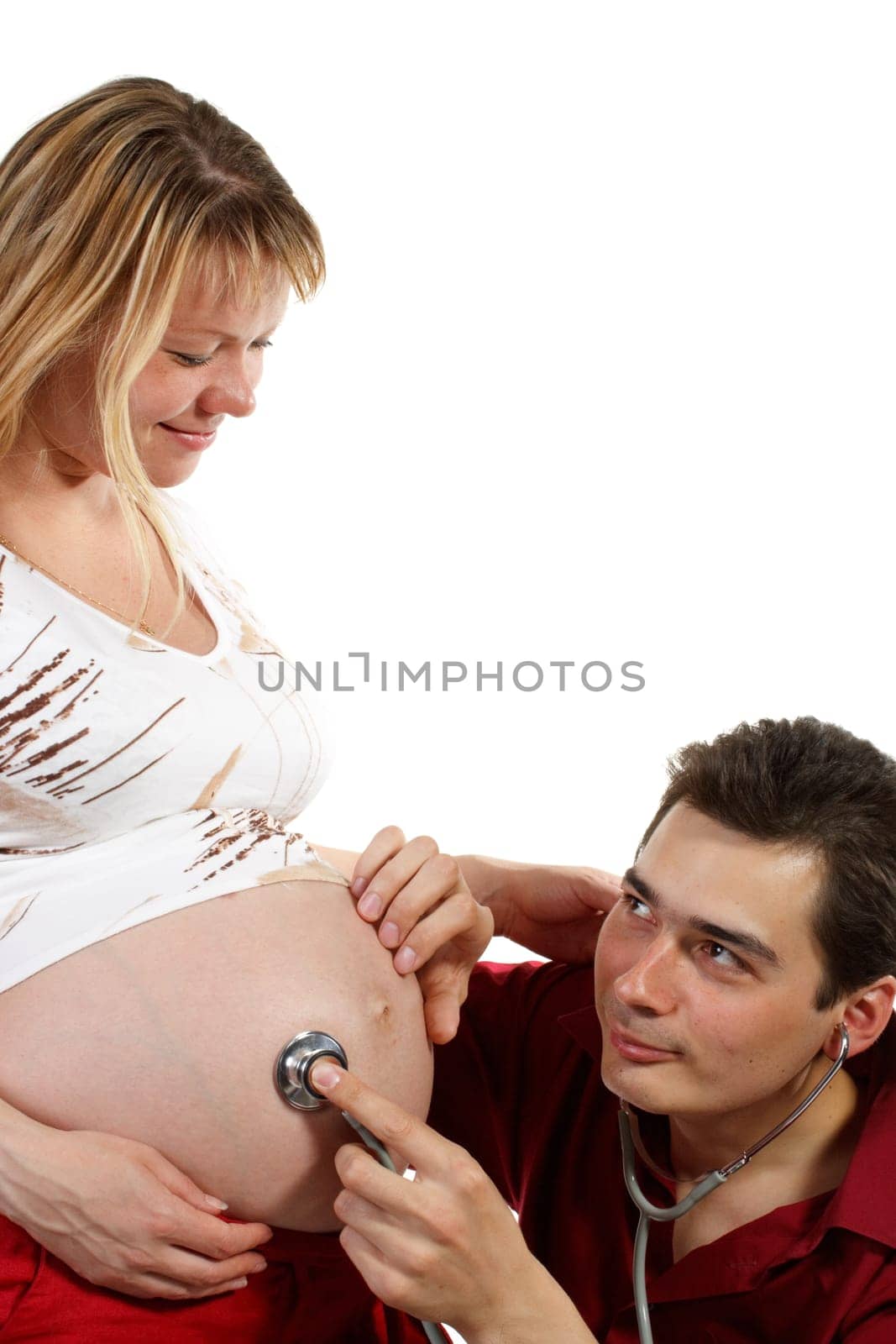 Young father listening heartbeat of his future child on a white background