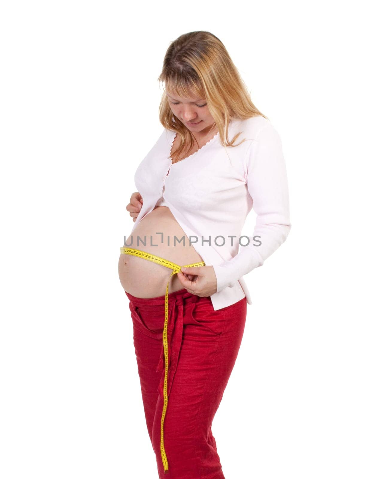 Pregnant woman measures her belly on a white background