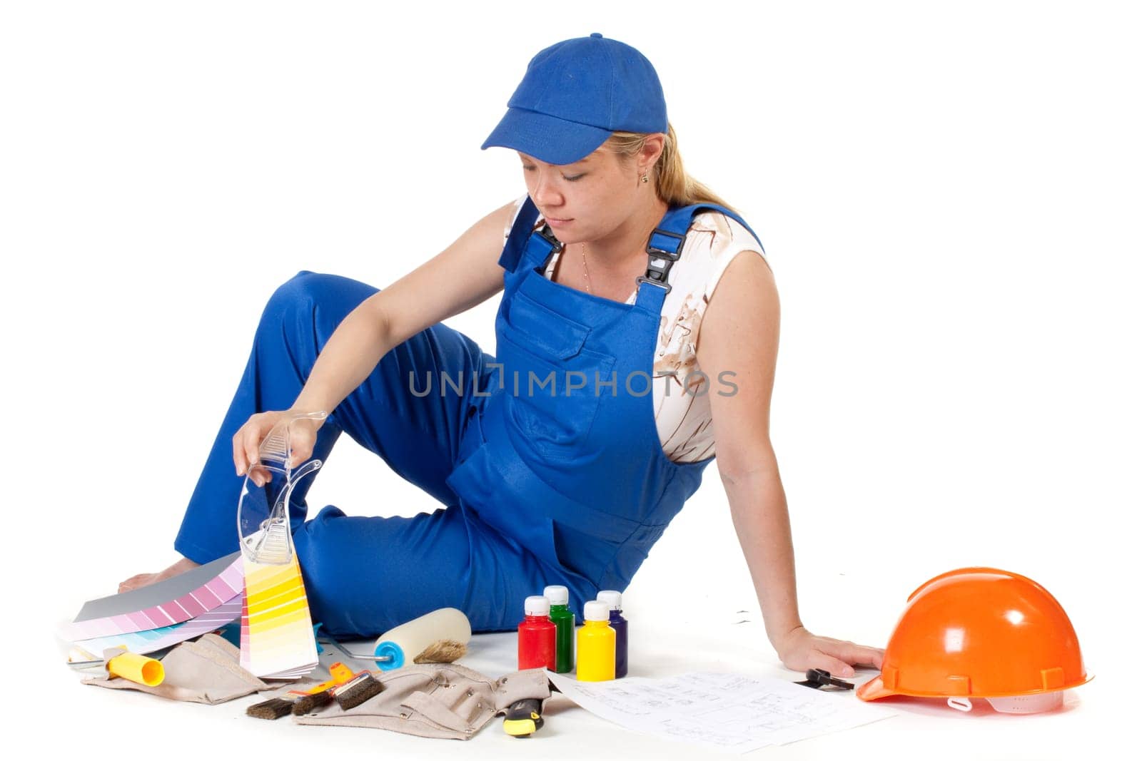 The pregnant woman dressed in working overalls, chooses colour for a children&#039 s room.