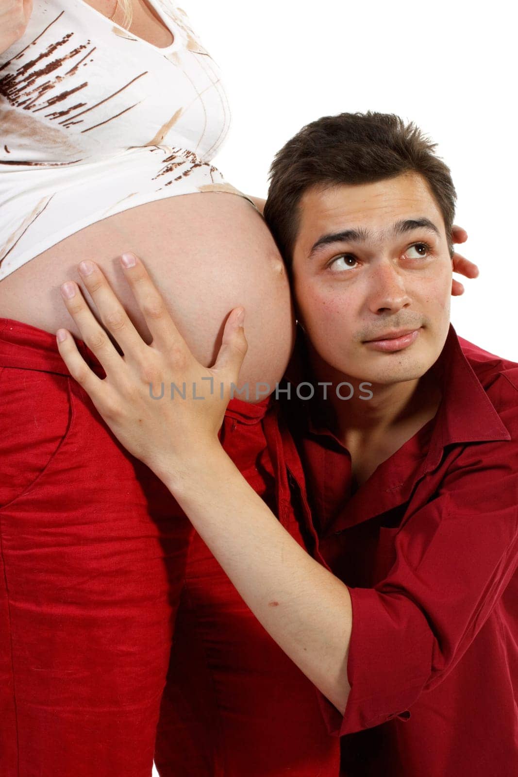 Young father listening heartbeat of his future child on a white background