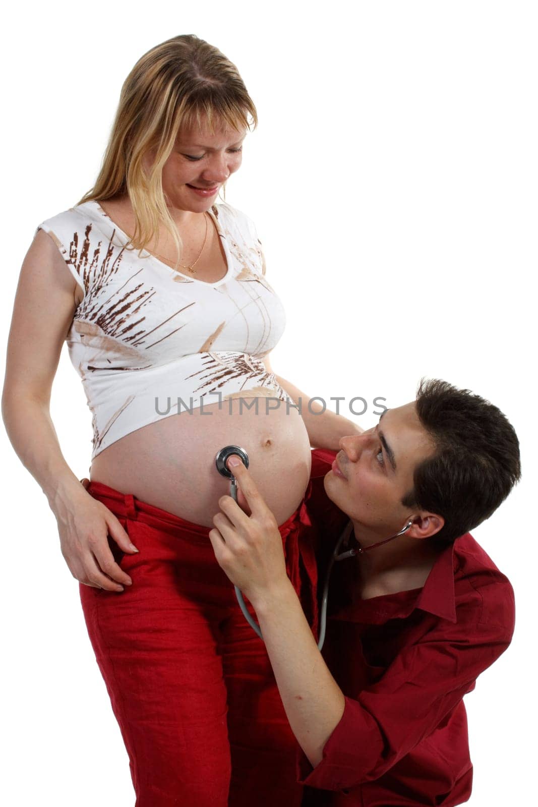 Young father listening heartbeat of his future child on a white background