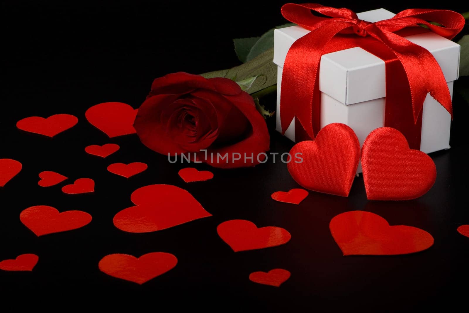 Gift box, red hearts and rose on a black background. Valentine&#039 s day card.