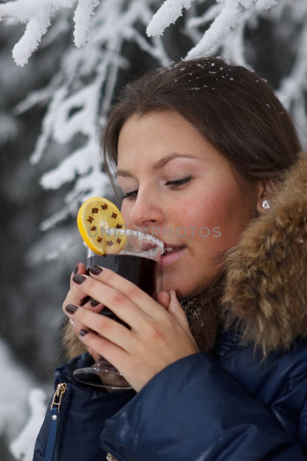 The beautiful girl drinks mulled wine in winter wood.