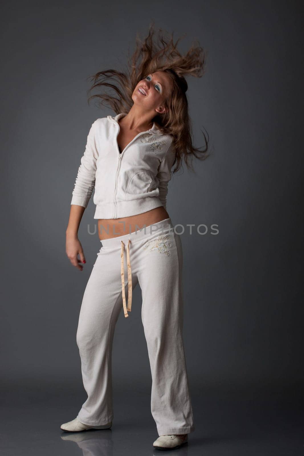The beautiful dancing girl on a grey background. Modern dances.