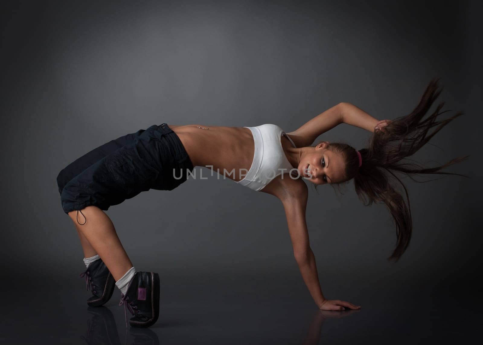 The beautiful dancing girl on a grey background. Modern dances.