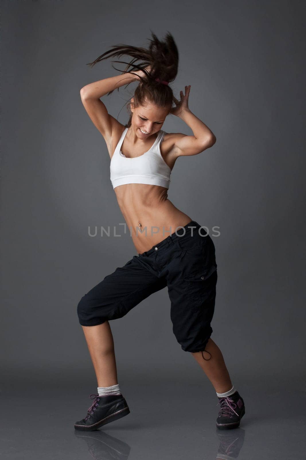 The beautiful dancing girl on a grey background. Modern dances.