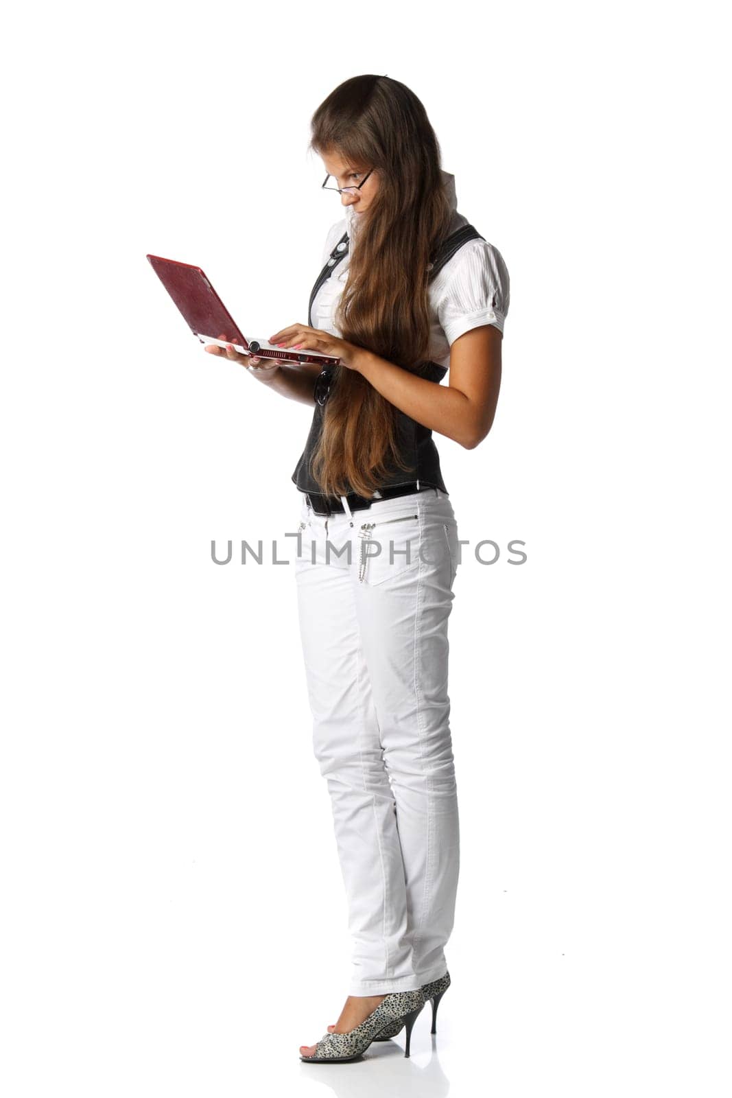 The attractive young woman stands with the laptop on a white background.