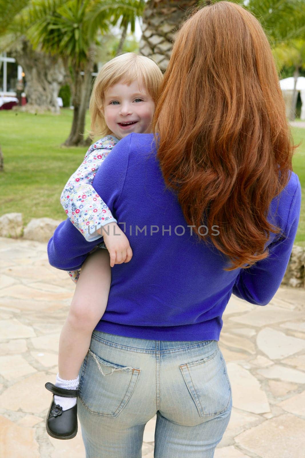 Redhead mother and blond daughter playing on the green park