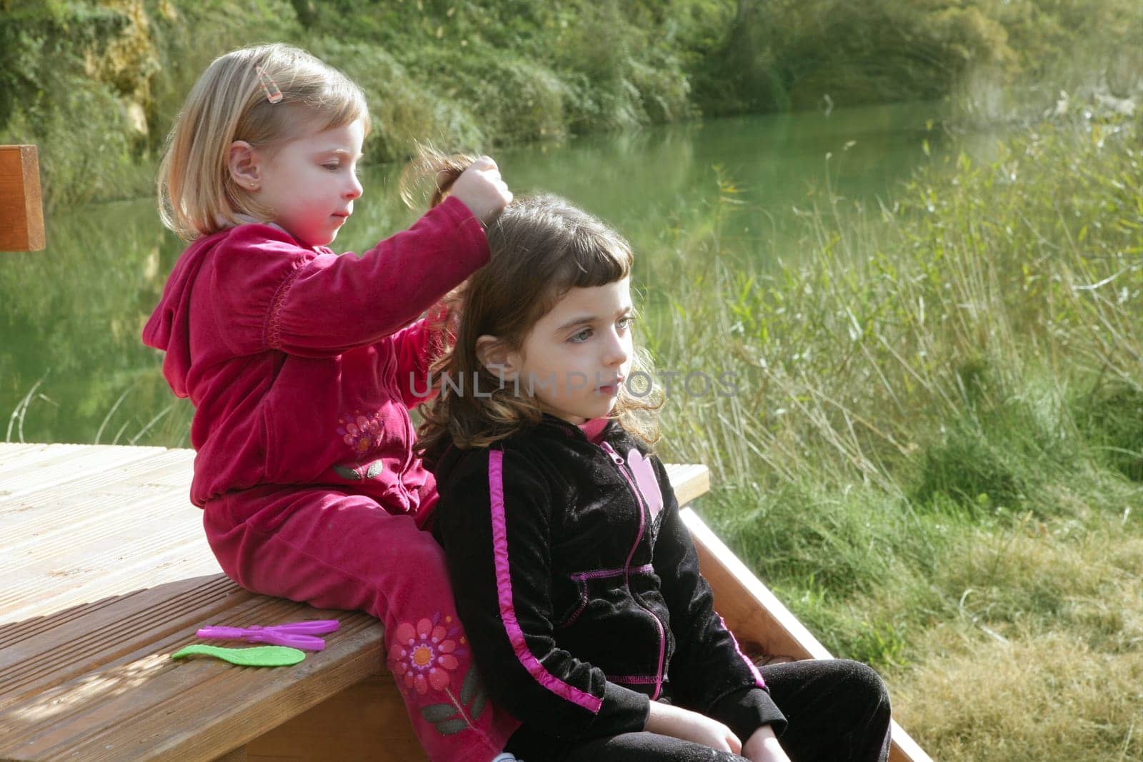 Little sister girls hairdresser on the river ourdoor park