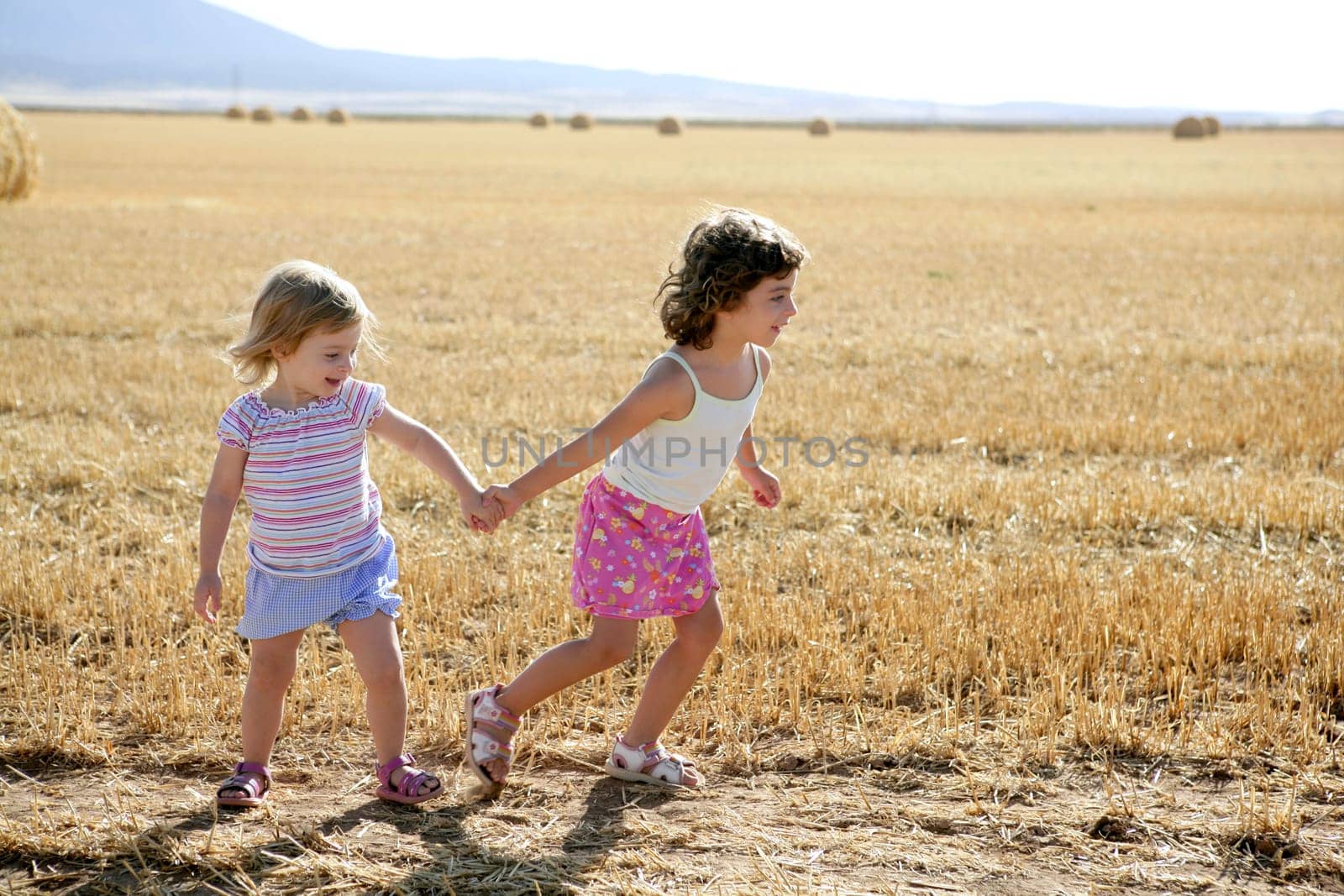 Girls playing with the round wheat dried bales outdoor summer