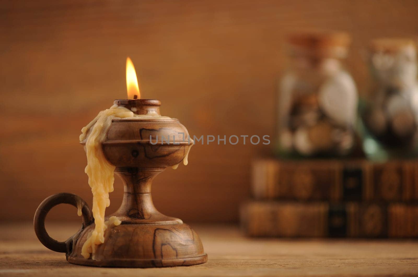 old candle on a wooden table, old books in the background