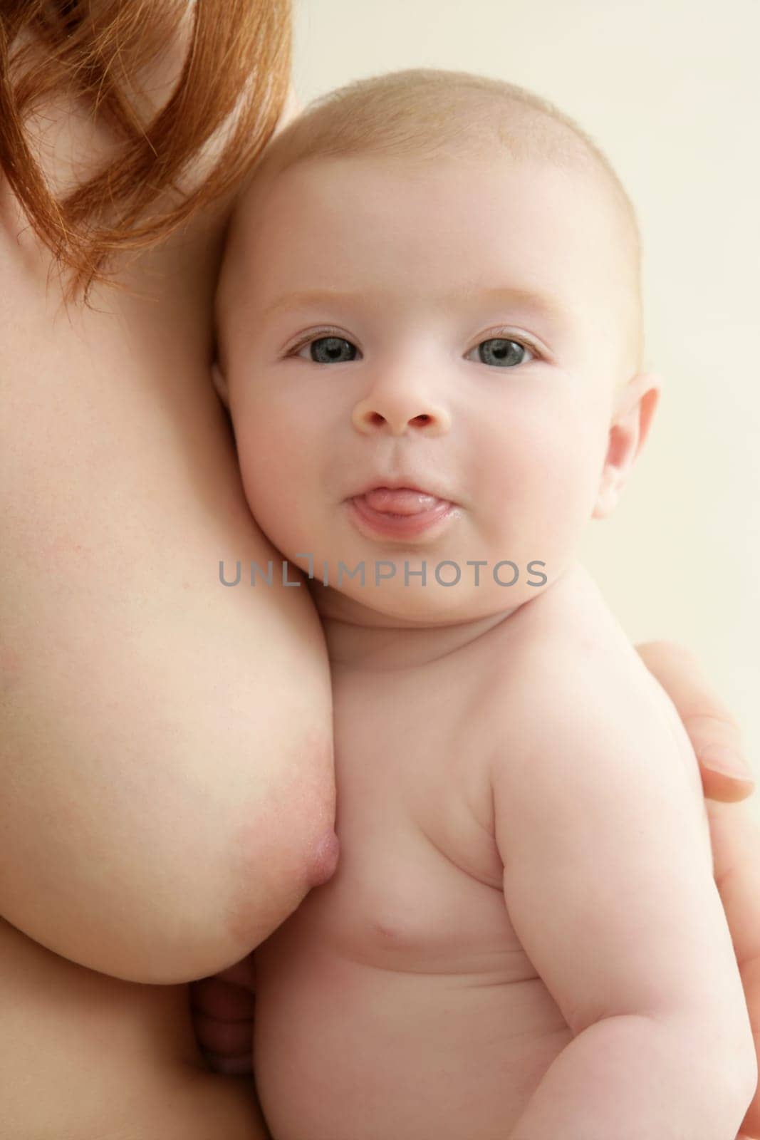 mother holding nude baby in arms on her breast
