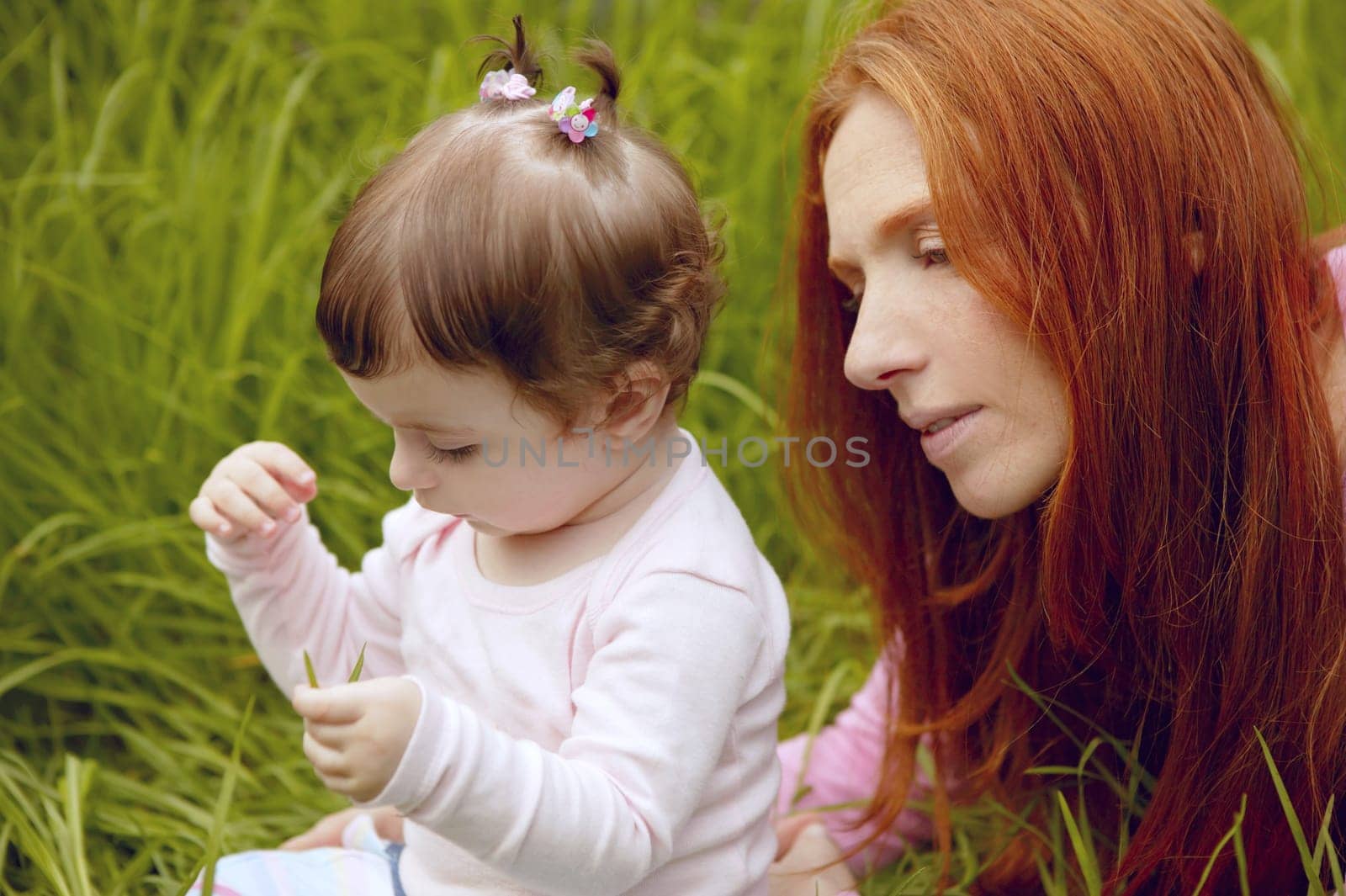 baby and redhead mother outdoor grass playing park together