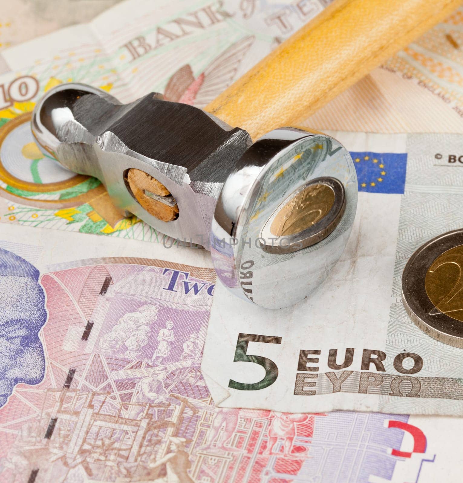 Macro of shiny hammer on top of euro note to illustrate currency crisis in Europe