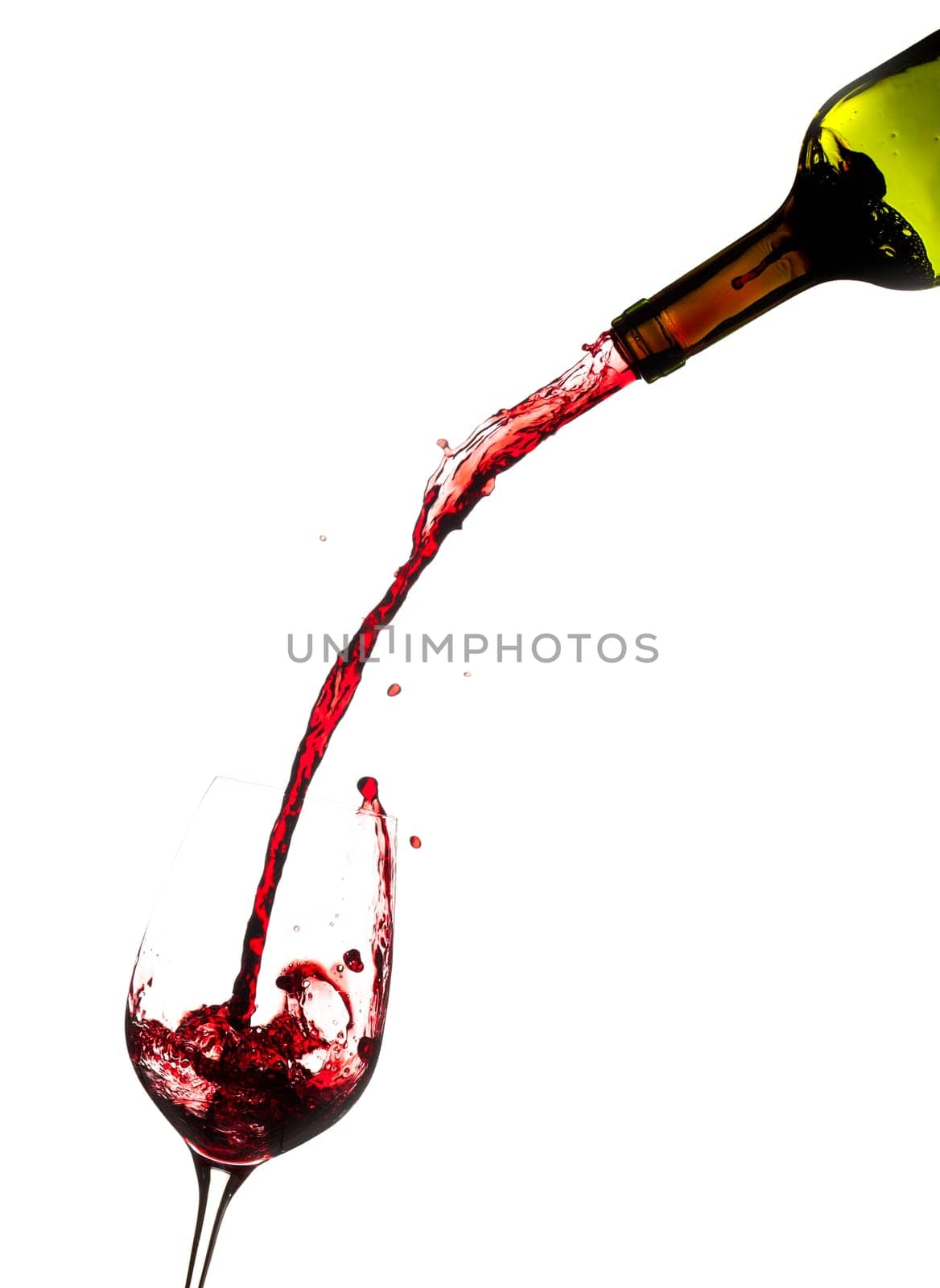 Red wine being poured directly from bottle into a large goblet