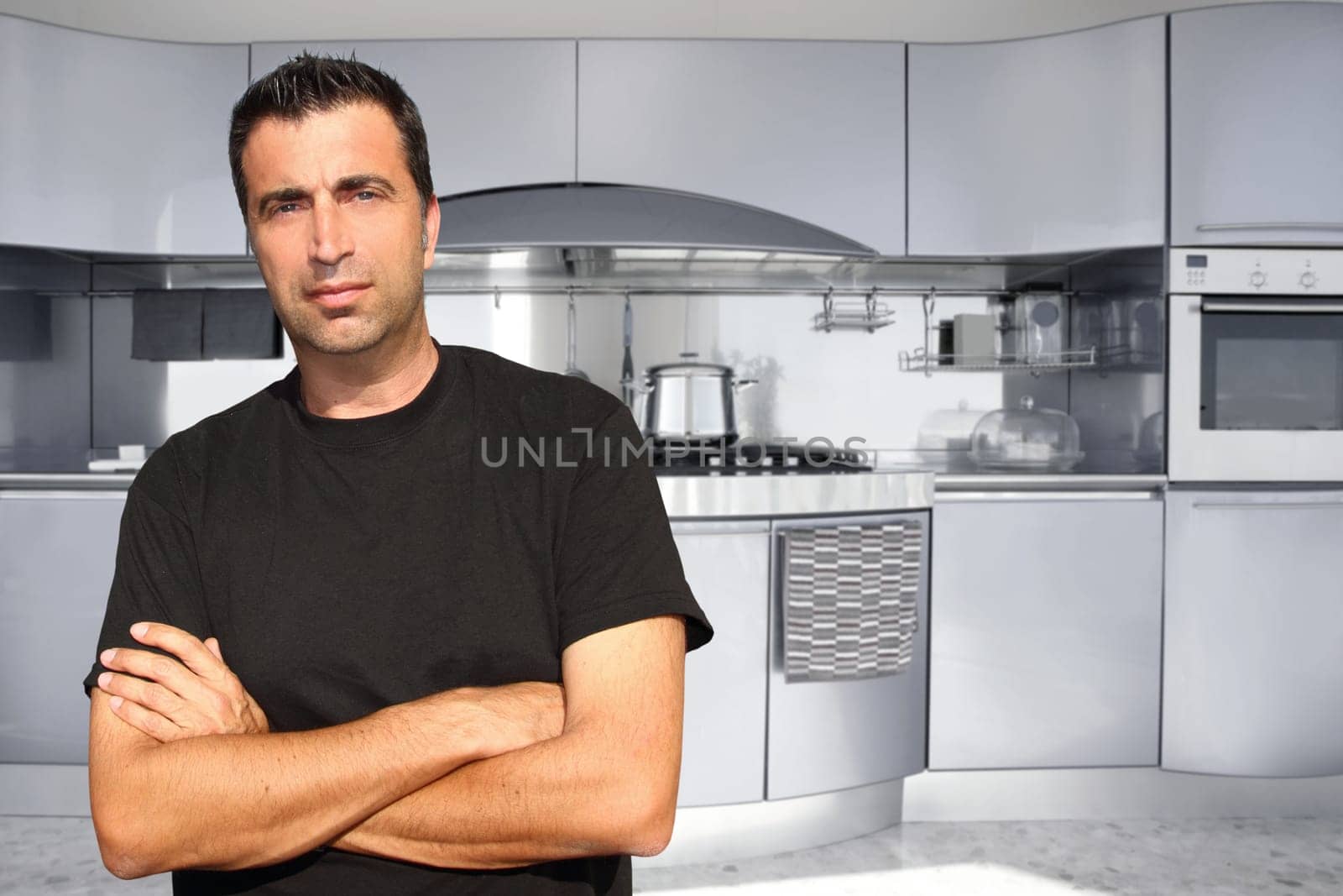 Medium age man in modern kitchen interior portrait crossed arms