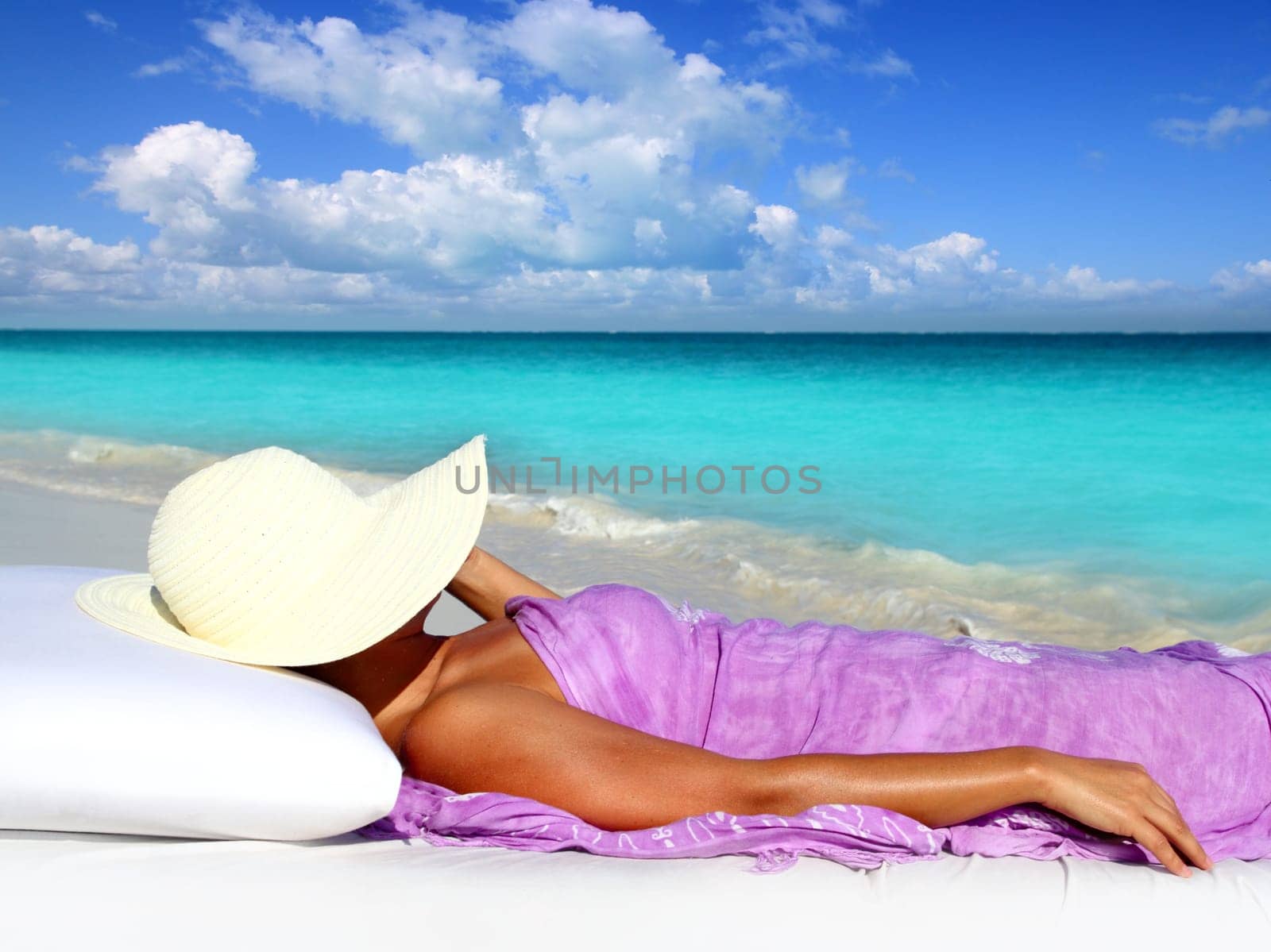 Caribbean tourist resting in tropical beach with hat lying on resort bed