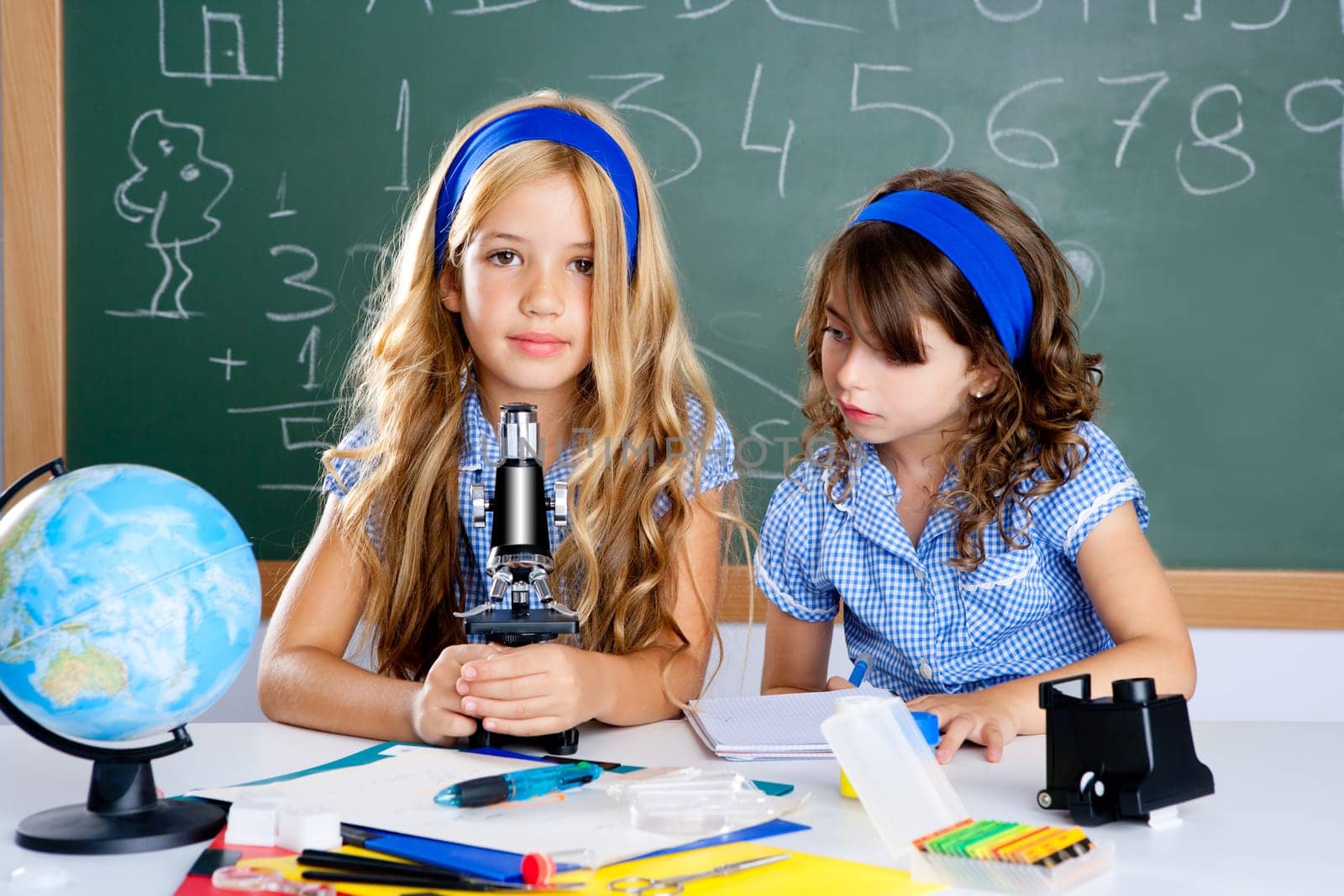 children girls at school classroom with world map and microscope