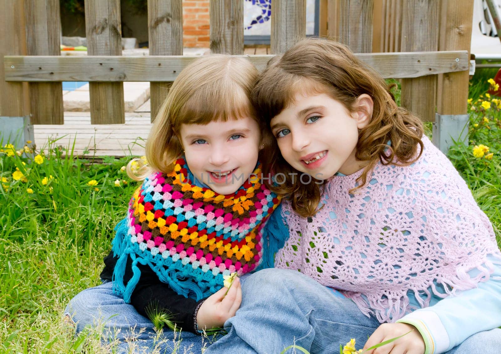 children sister girls smiling in meadow spring fence yellow flowers