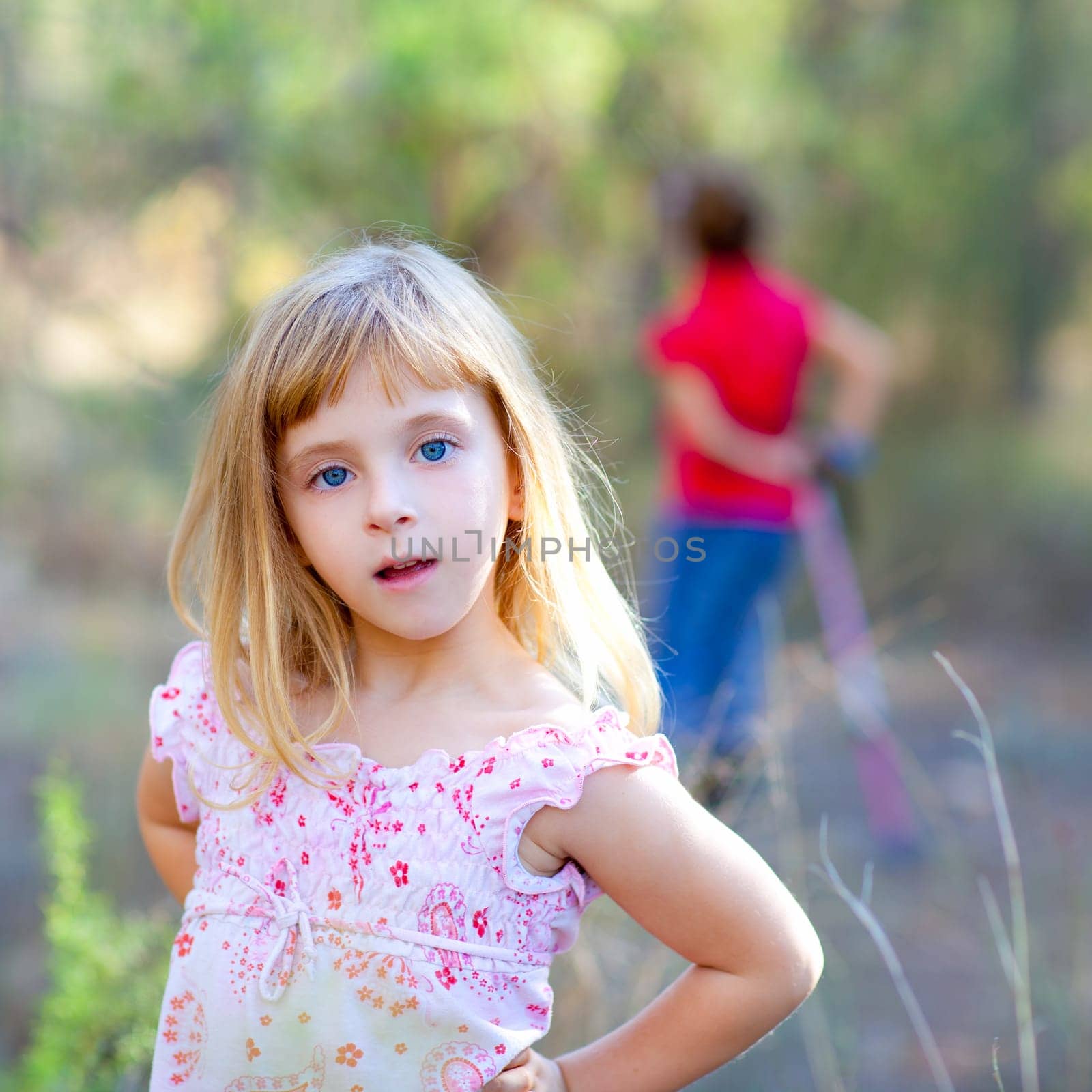 blond kid girl in forest park posing to camera