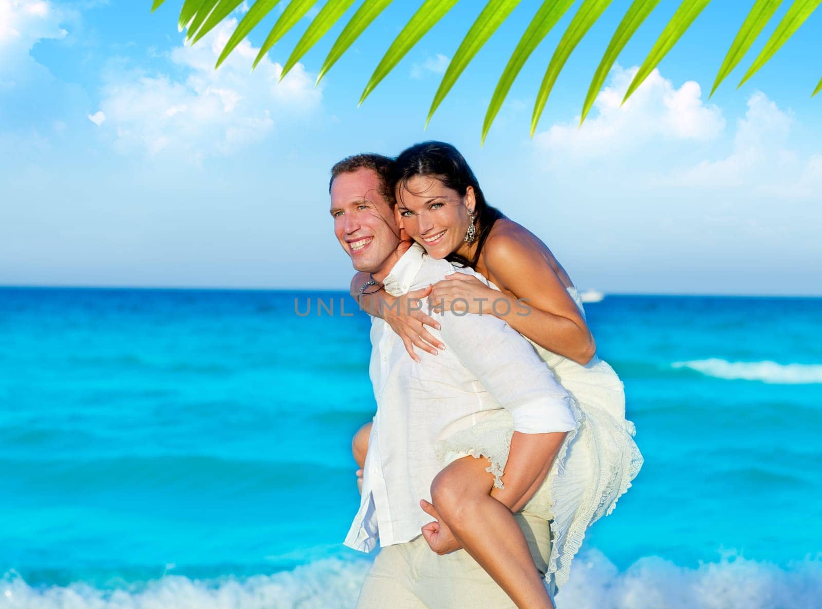 couple in love piggyback playing in a beach at blue Mediterranean