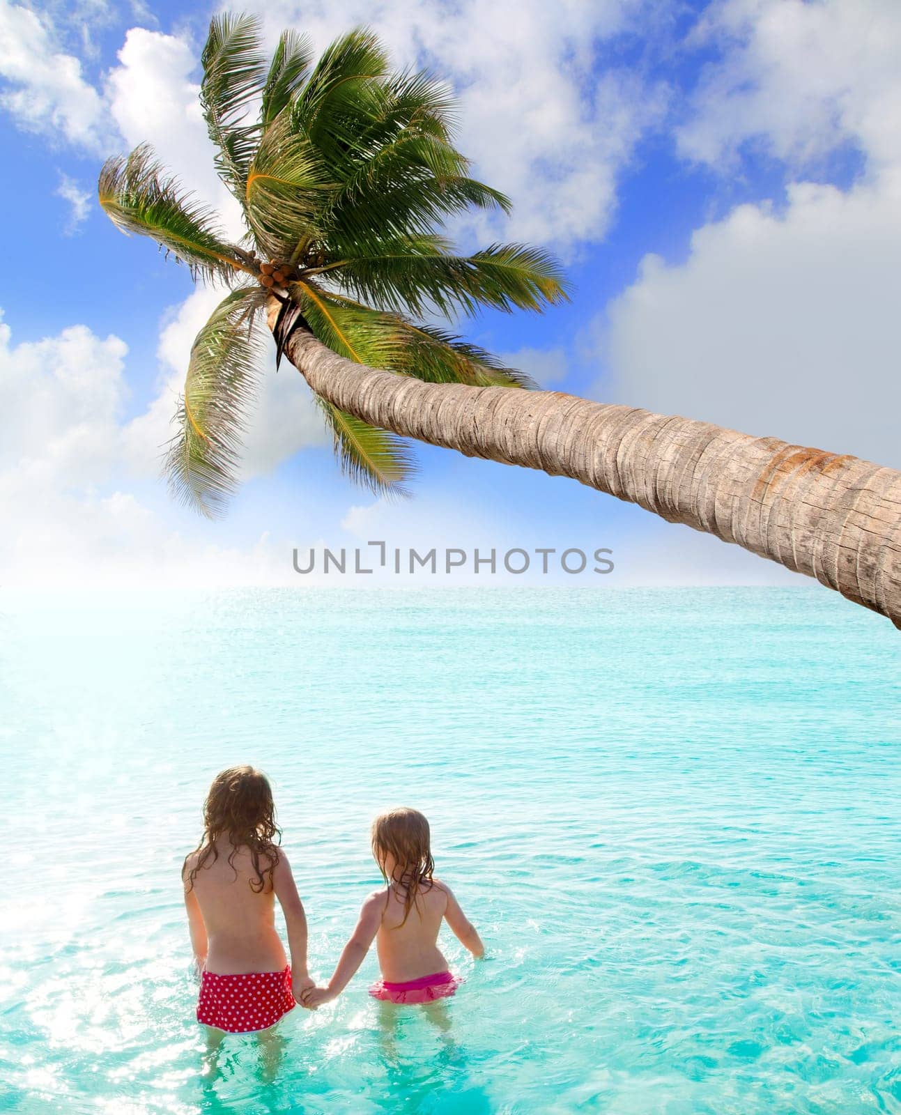 children girls rear view in the beach looking at sunset