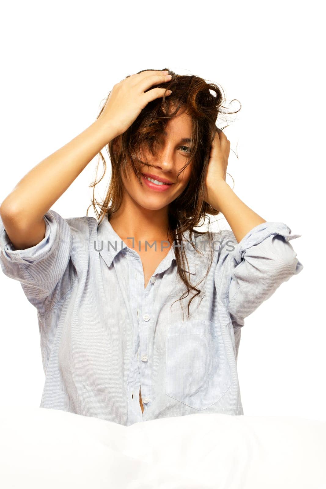 Happy woman in pajamas playing with her hair against white background