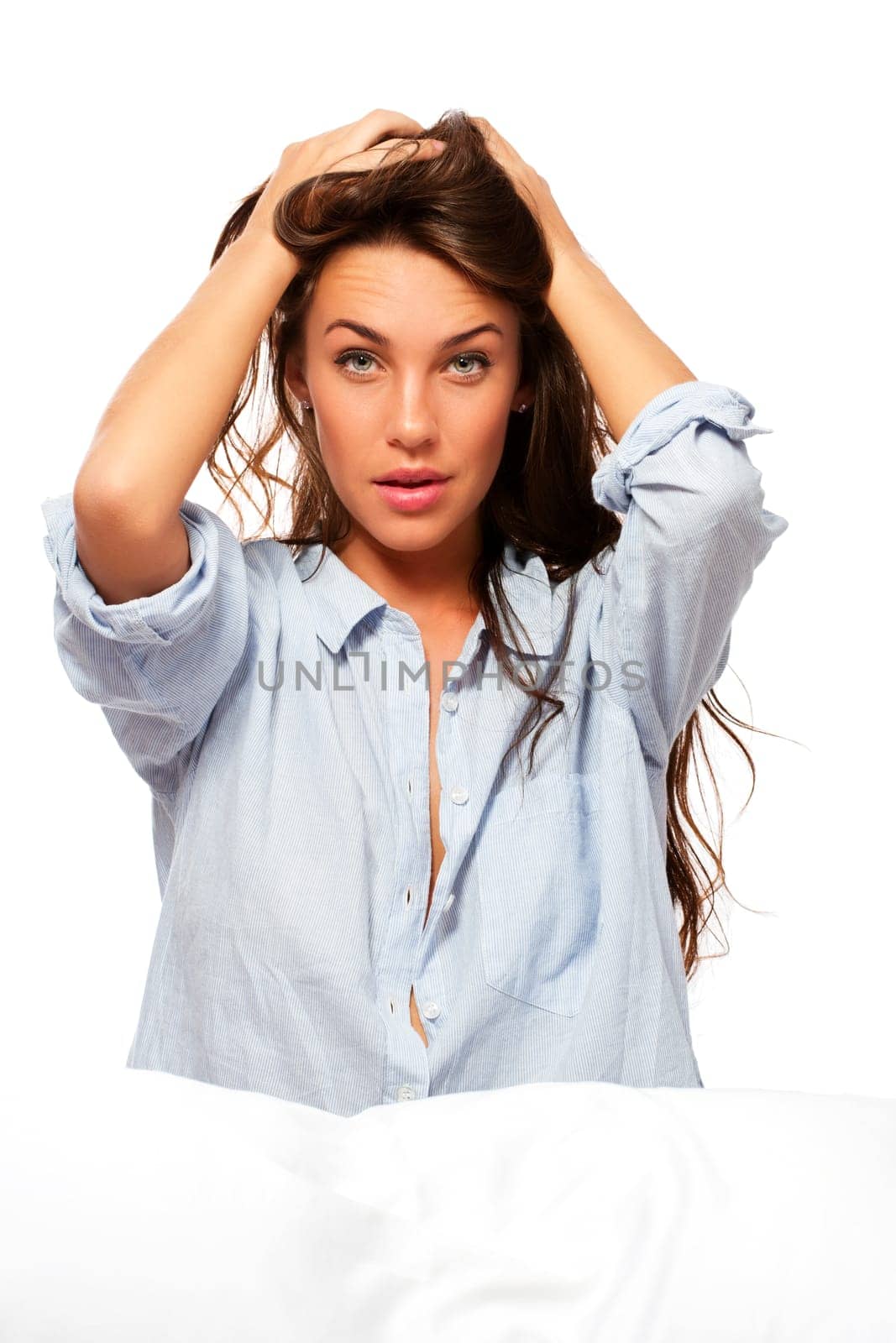 Beautiful woman sitting in bed and holding her hair against white background
