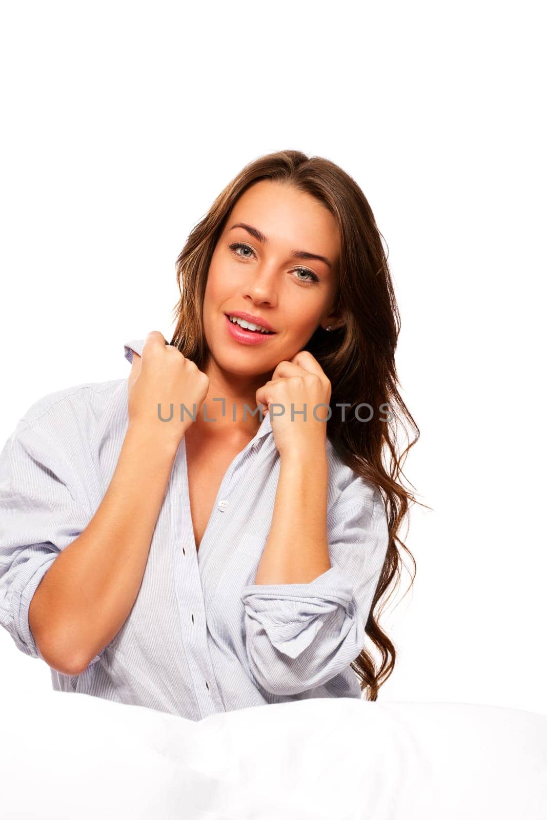 Beautiful woman in bed holding collar of her pajamas against white background